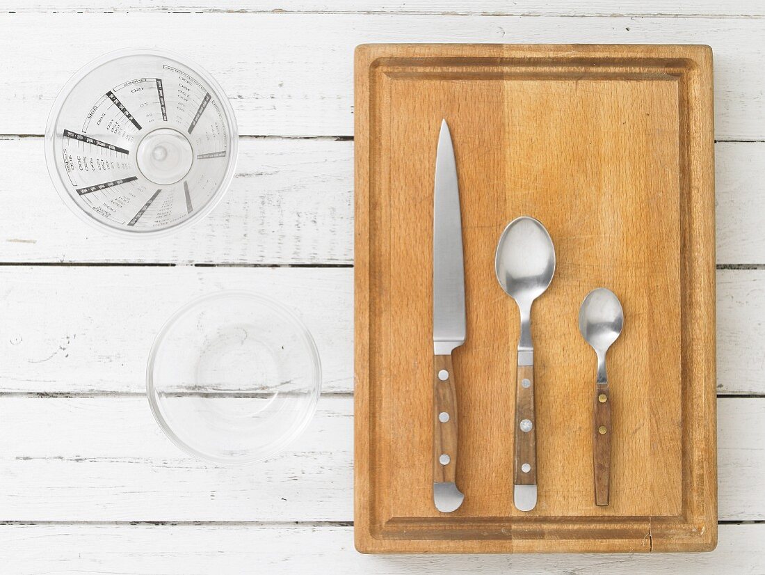 Kitchen utensils: a measuring jug, a glass bowl, a knife and spoons