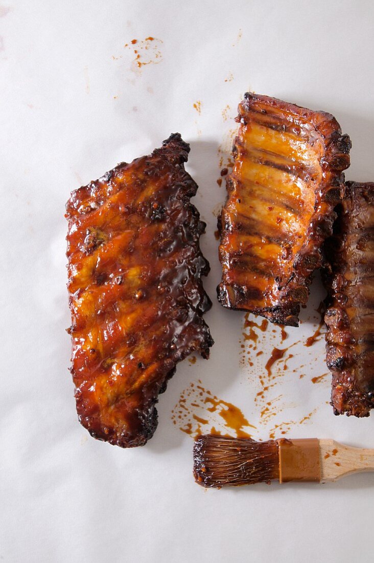 Barbecued pork ribs on a white surface (seen from above)