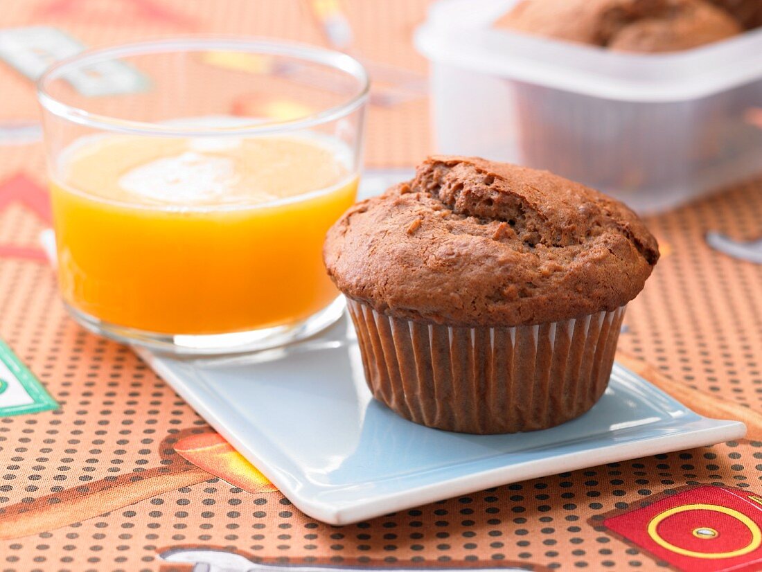 A chocolate muffin with honey served with a glass of orange juice
