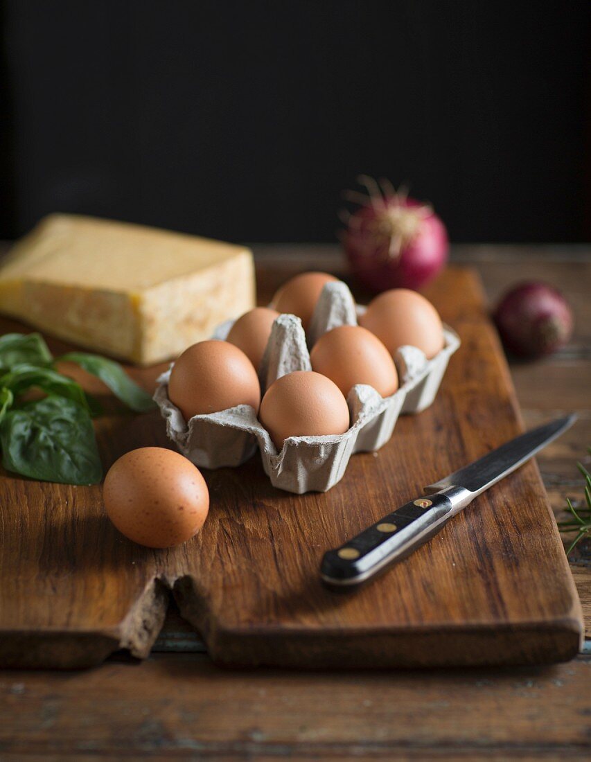 Zutatenstilleben mit Eiern, Käse, Kräutern und Zwiebeln