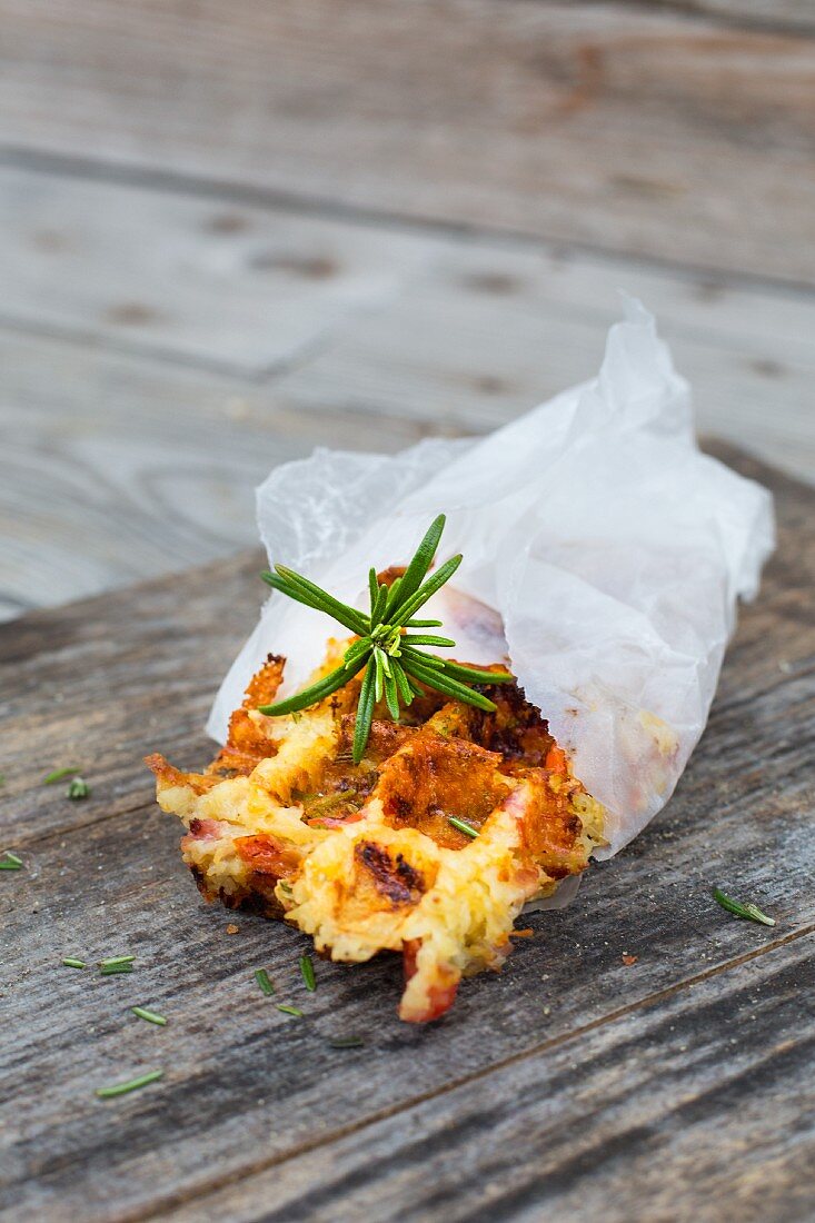 A piece of rosemary and potato waffle in greaseproof paper