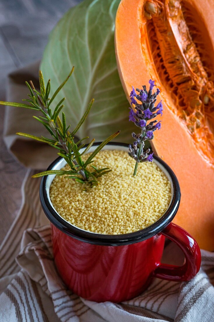 Couscous in an enamel mug with a pumpkin and white cabbage in the background