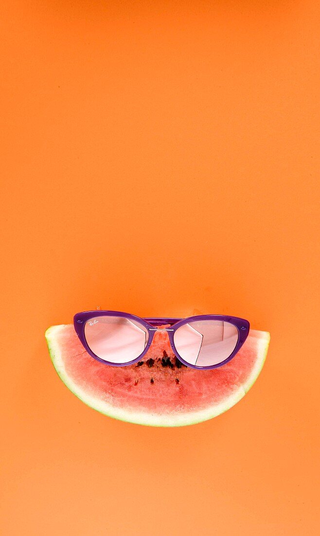 A slice of watermelon wearing purple sunglasses