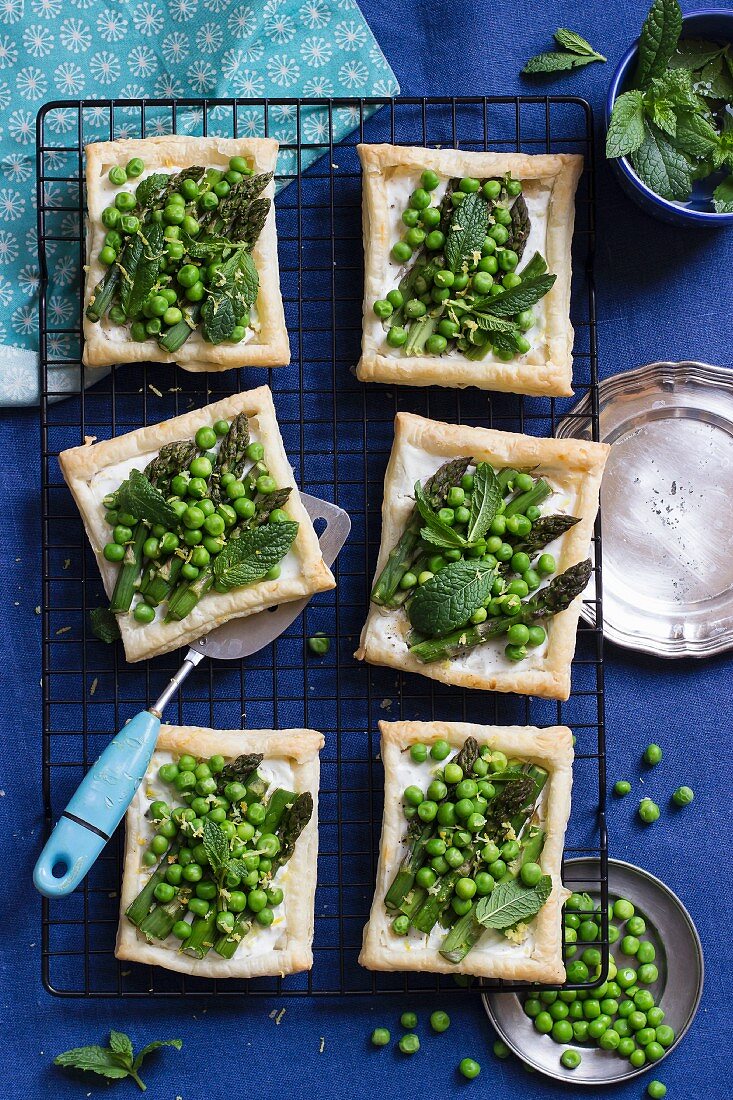 Puff pastry tartlets topped with asparagus, green peas, mint, goat's cheese and lemon zest