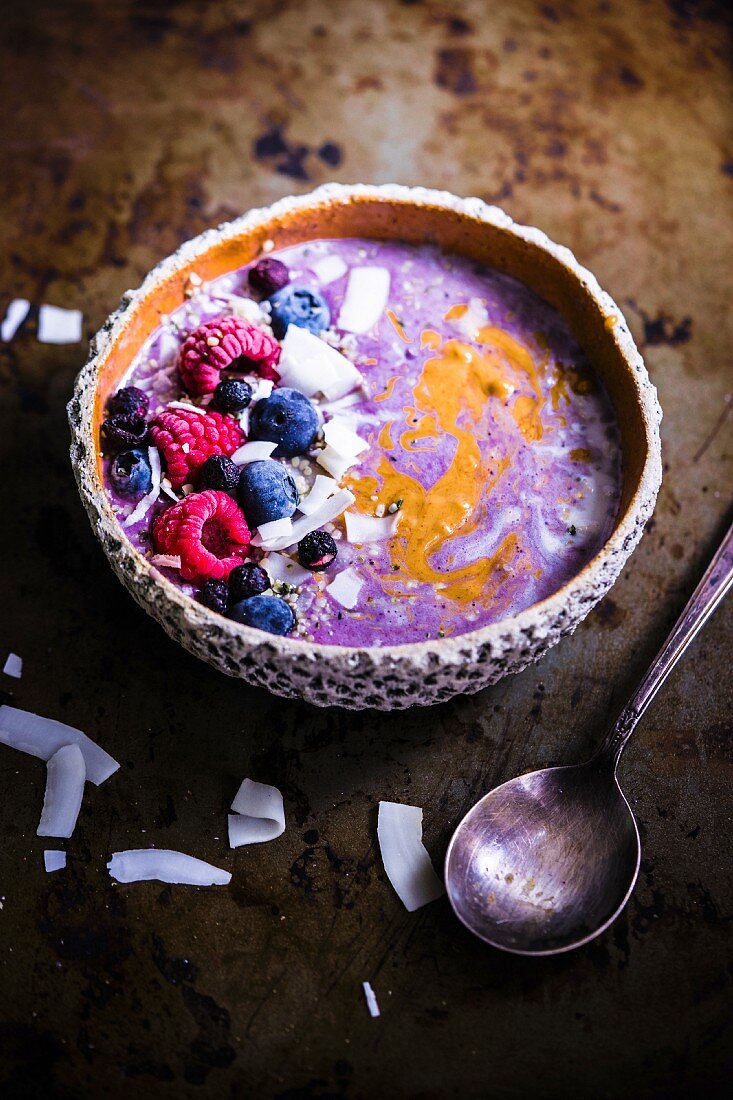 A smoothie bowl with oats, chia seeds, grated coconut, almond butter and blueberry compote
