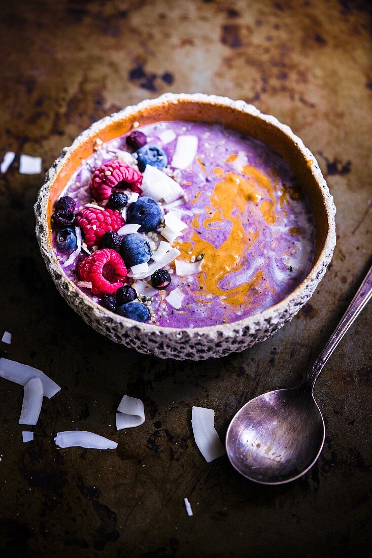 Smoothie Bowl mit Haferflocken, Chiasamen, Kokosspänen, Mandelbutter und Heidelbeerkompott