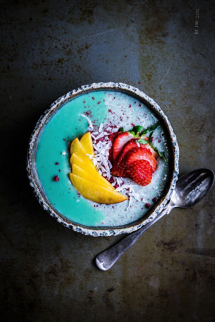 Spirulina and chia pudding with peach, strawberries and grated coconut