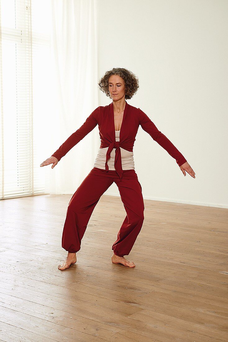 Carrying the ball in front of shoulders (qigong) – Step 6: lower, turn right, arms to the side