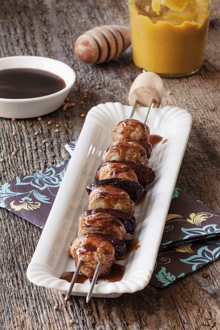 A sausage kebab with dates and a honey mustard sauce