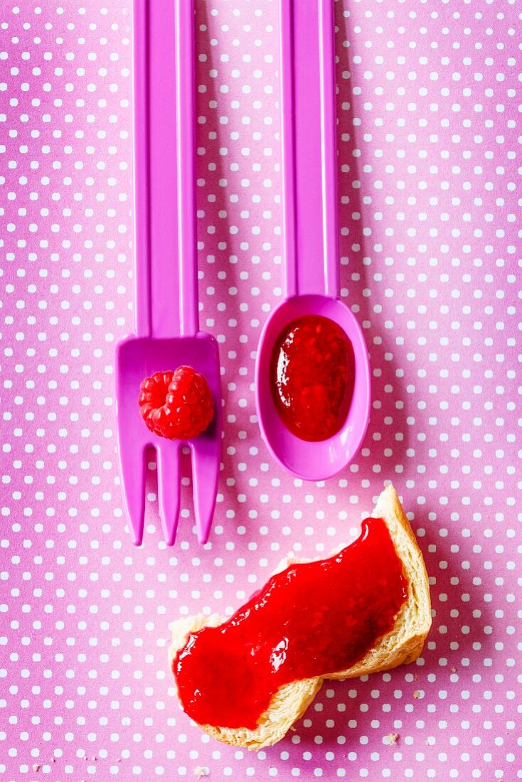A raspberry face made with cutlery, berries, jam and a piece of bread