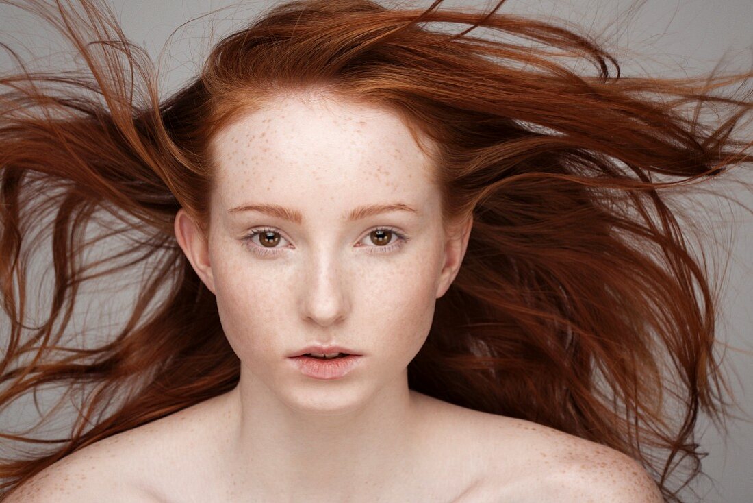 Junge Frau mit wehenden roten Haaren