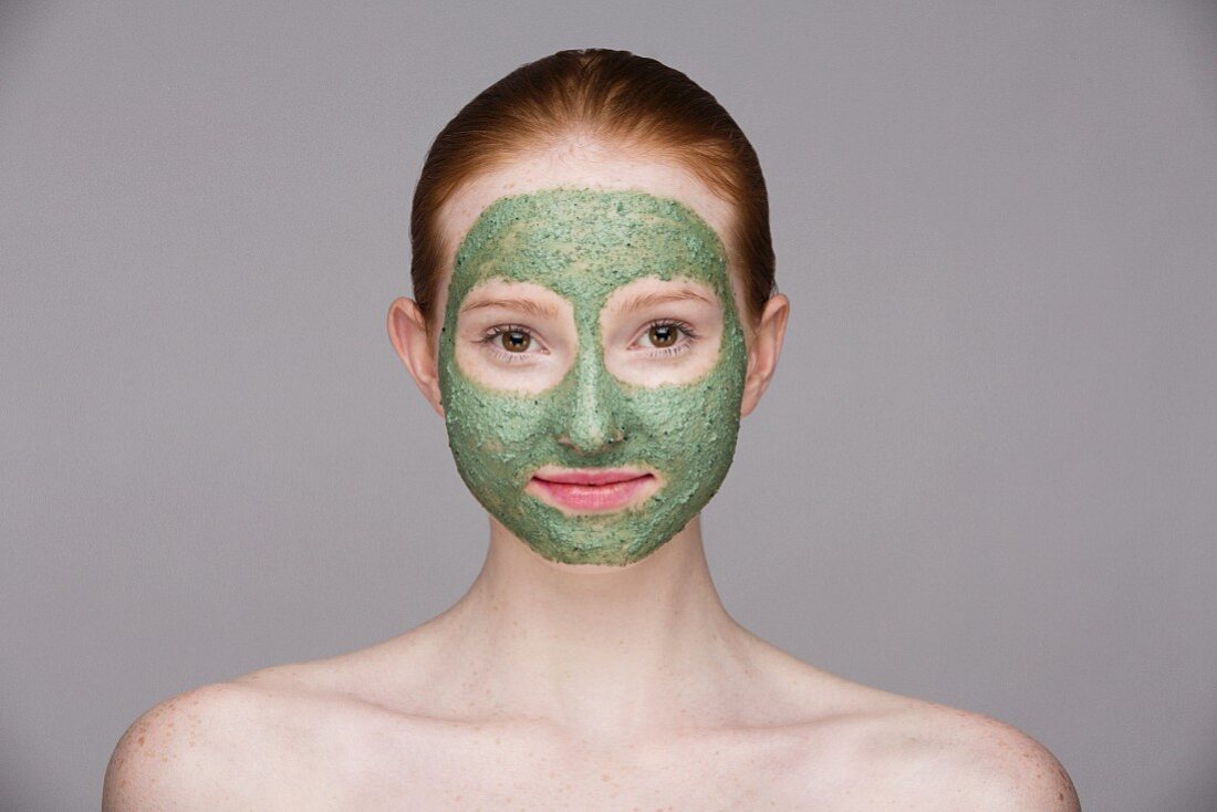 Junge Frau mit grüner Gesichtsmaske