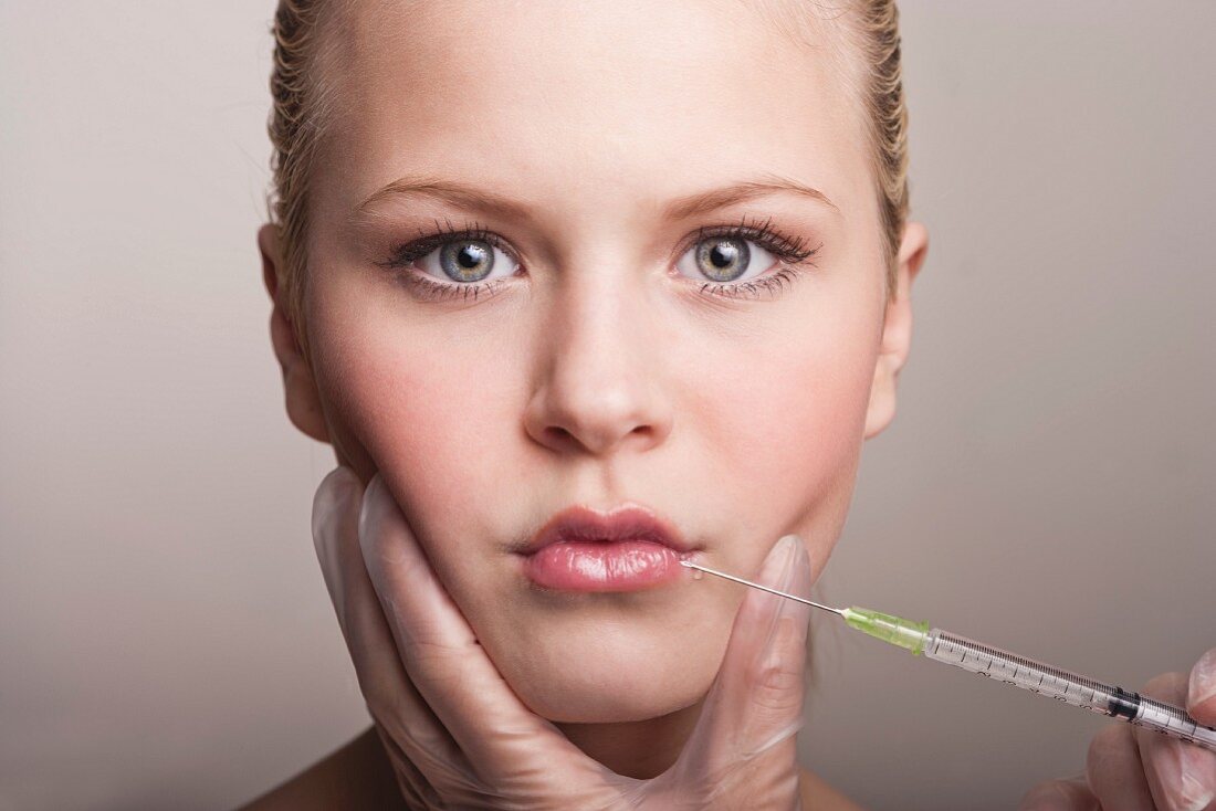A young woman getting Botox injected into her lips