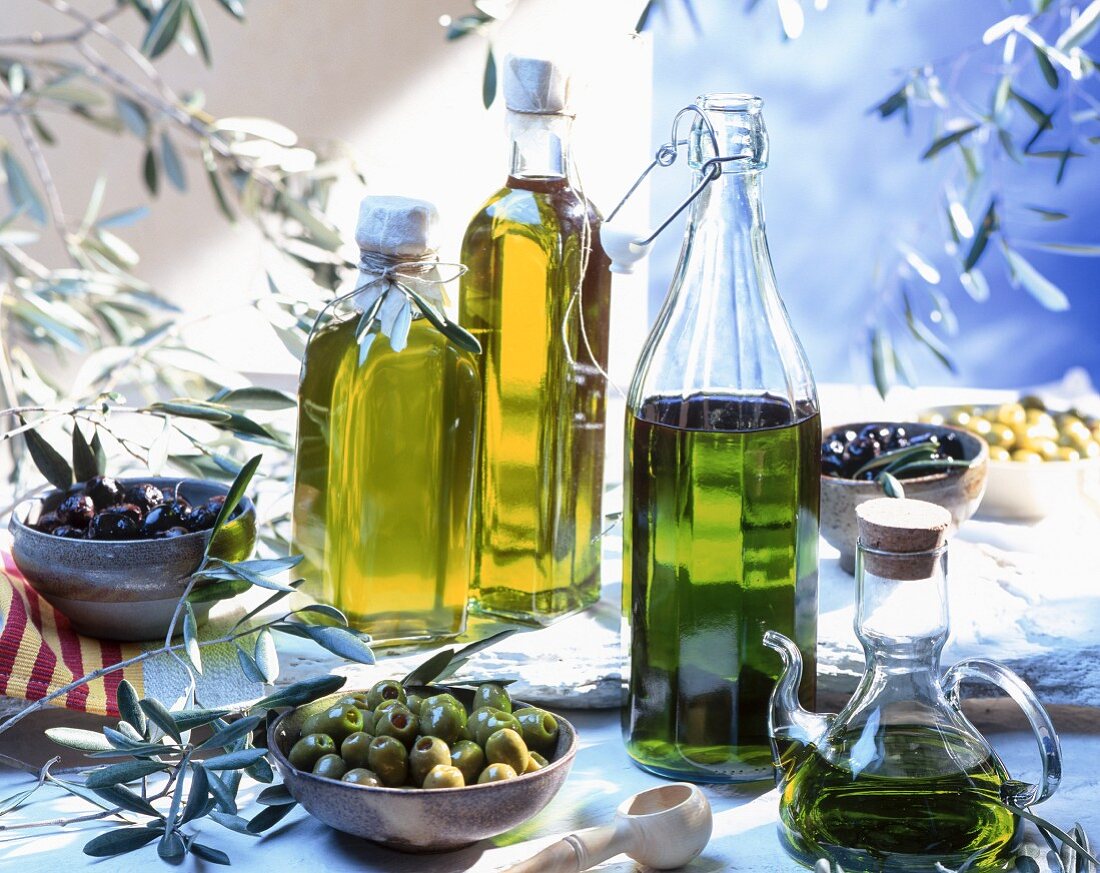Stillleben mit verschiedenen Oliven und Olivenölen