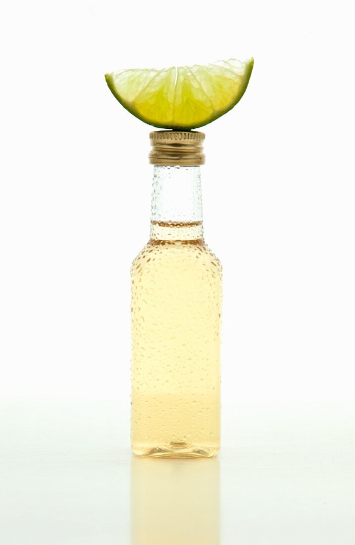 A small bottle of tequila with a lime wedge on top