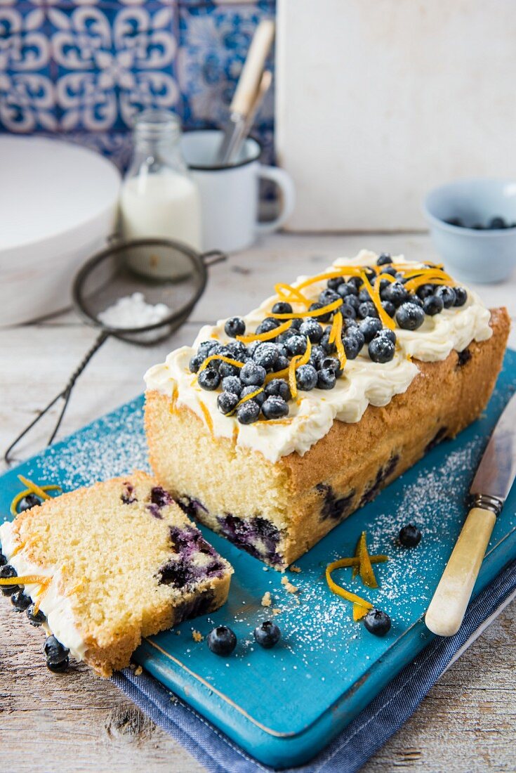 Blueberry loaf cake with cream cheese frosting and orange zest, sliced