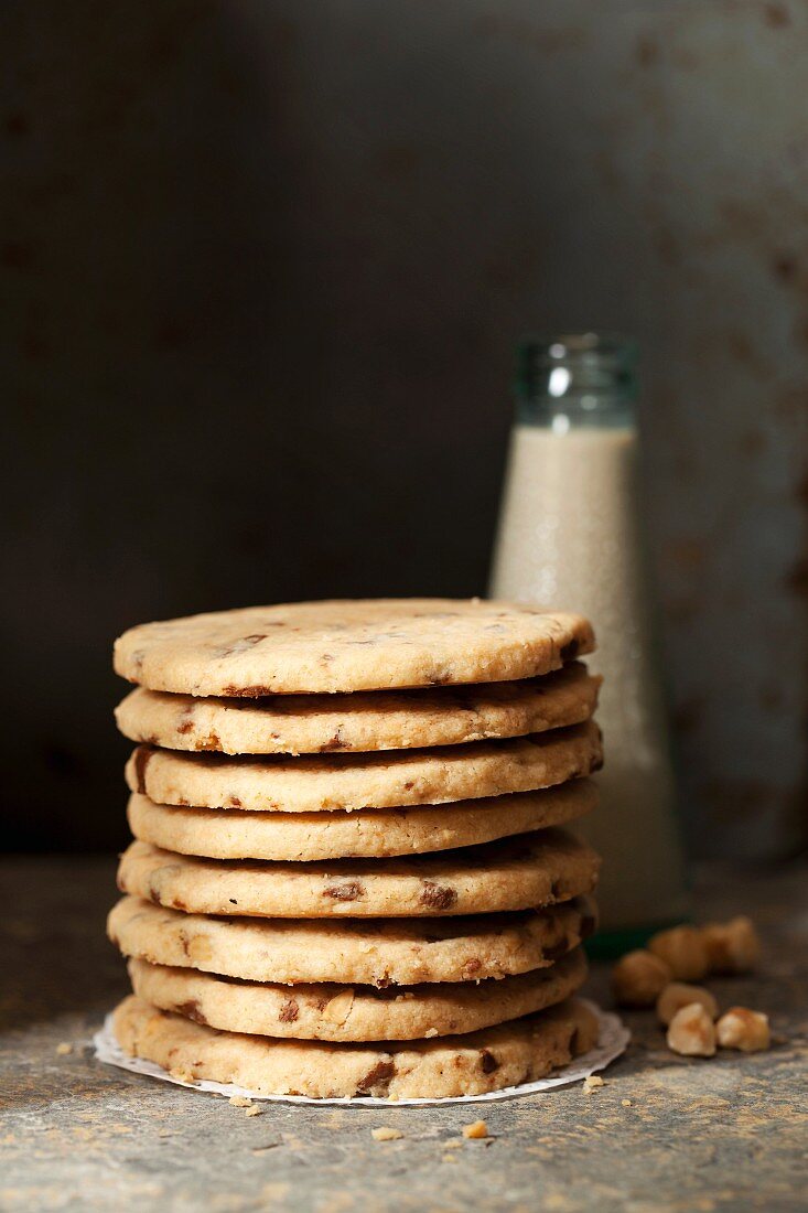 Gestapelte Haselnuss-Chocolatechip-Cookies vor Milchflasche