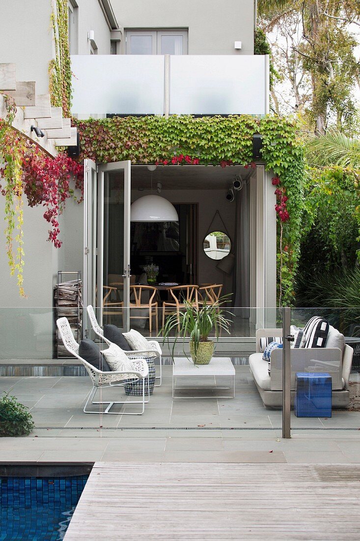 Terrace with lounge area behind glass balustrade and pool