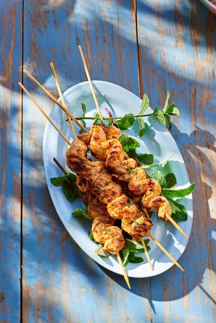 Chicken kebabs with mint on a table outside