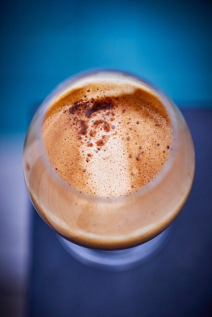 A view from above of a stemmed glass with coffee and coffee foam