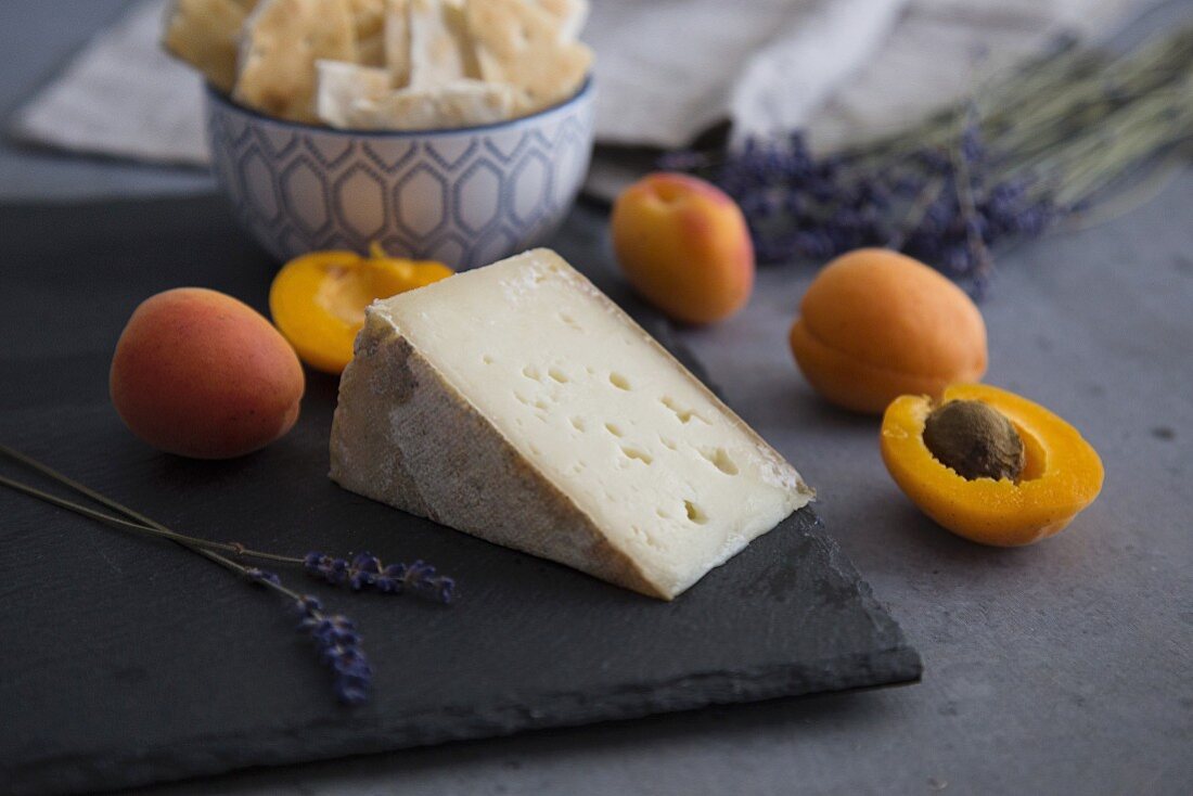 Apricots and goat's cheese on a slate platter with crackers and lavender flowers