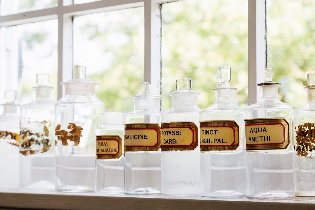 Row of apothecary jars with labels on windowsill