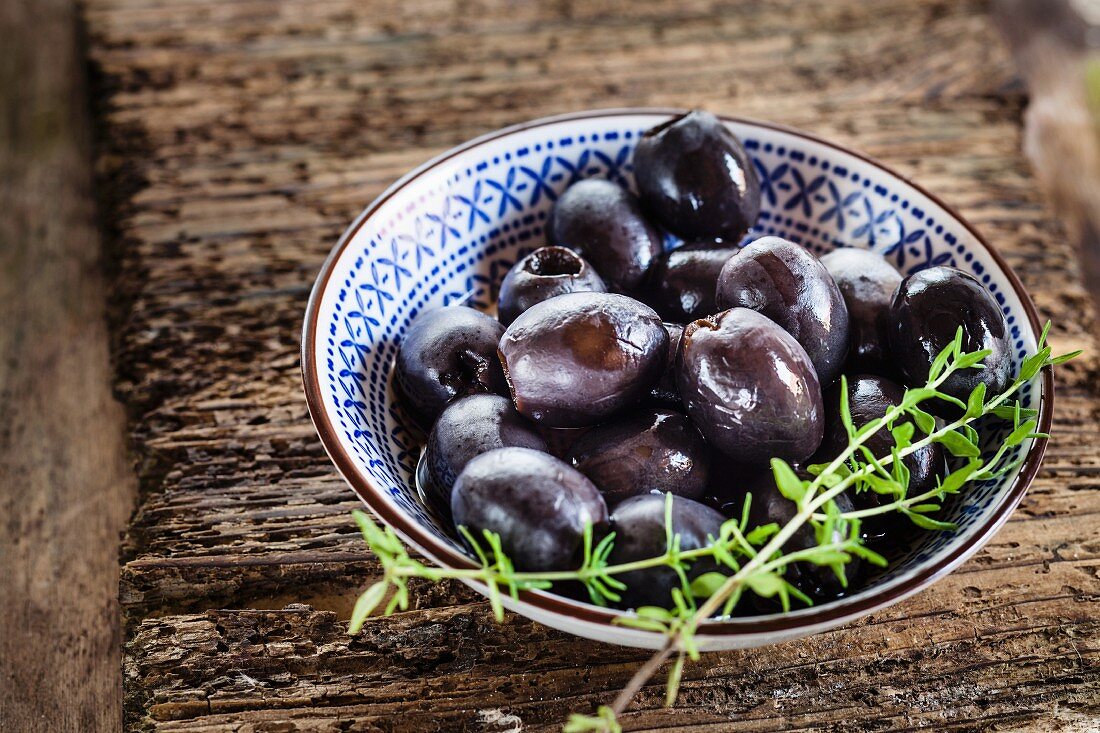 Eingelegte schwarze Oliven mit Thymianzweig