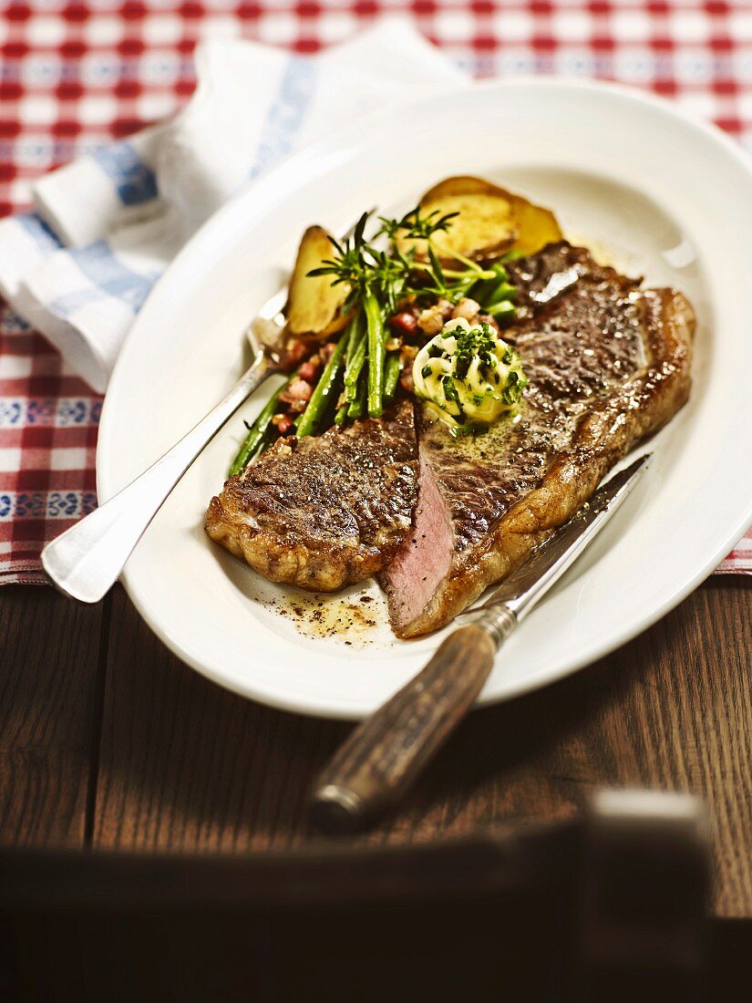 Pan-fried ox sirloin steak with herb butter and green beans with bacon