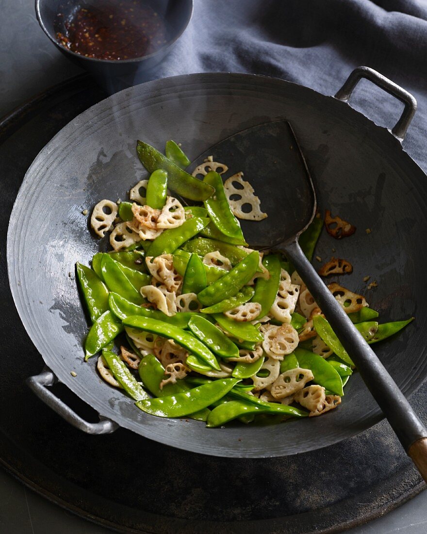 Gebratene Lotuswurzeln und Zuckerschoten im Wok