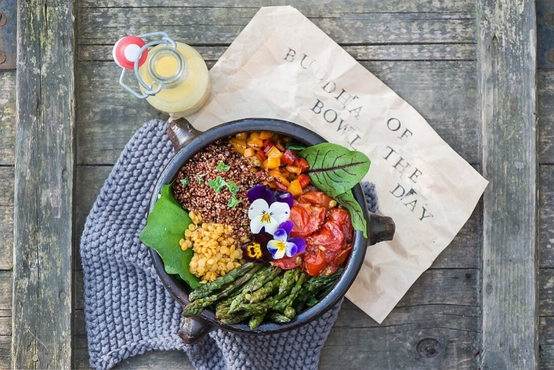 A Buddha Bowl with lentils, asparagus, tomatoes, peppers, lettuce and pansies