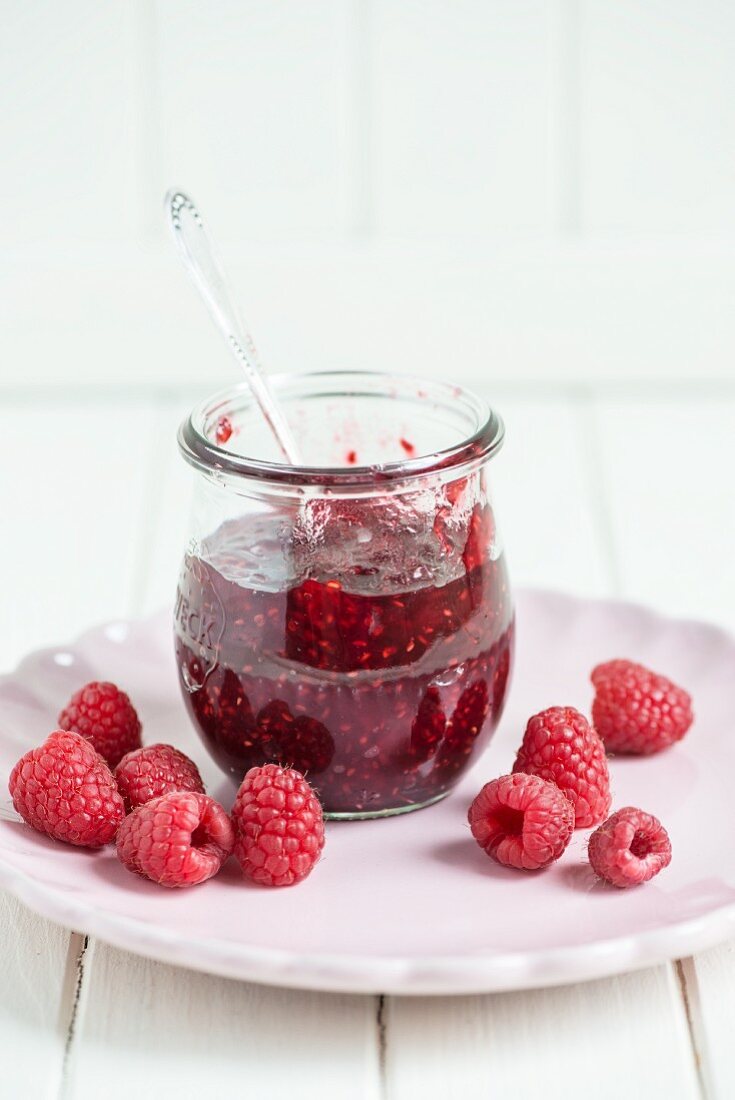 A jar of raspberry jam with a spoon