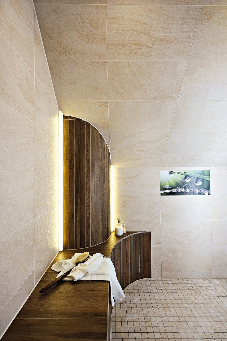 A designer bathroom with a bench and a semi-circular panel under a tiled roof slope