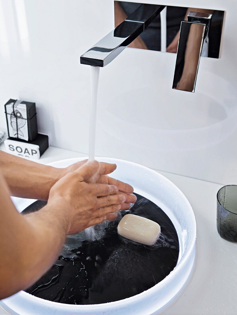 Washing over a white plastic bowl with a black base in a slate design and a wall-mounted designer tap