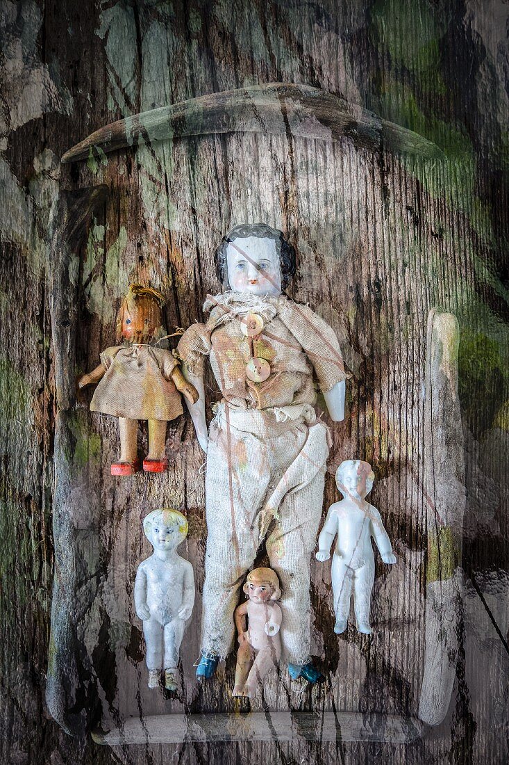 Macabre arrangement of antique dolls on wooden tray