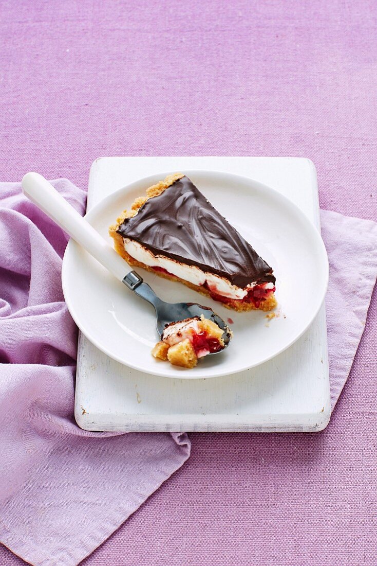 Ein Stück Wagenrad-Tarte mit Marshmallows, Himbeeren und Schokoladenglasur