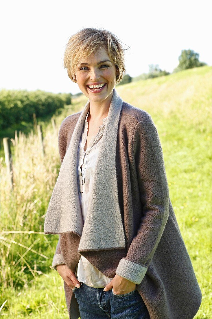 A young blonde woman wearing a natural coloured blouse and a woollen jacket