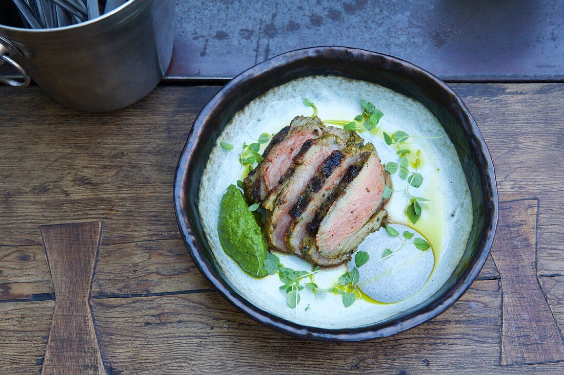 A lamb steak with white and green sauces