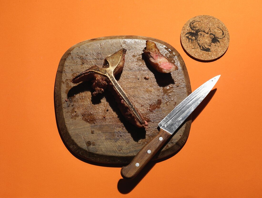 Die Reste eines T-Bone-Steaks auf Holzbrett