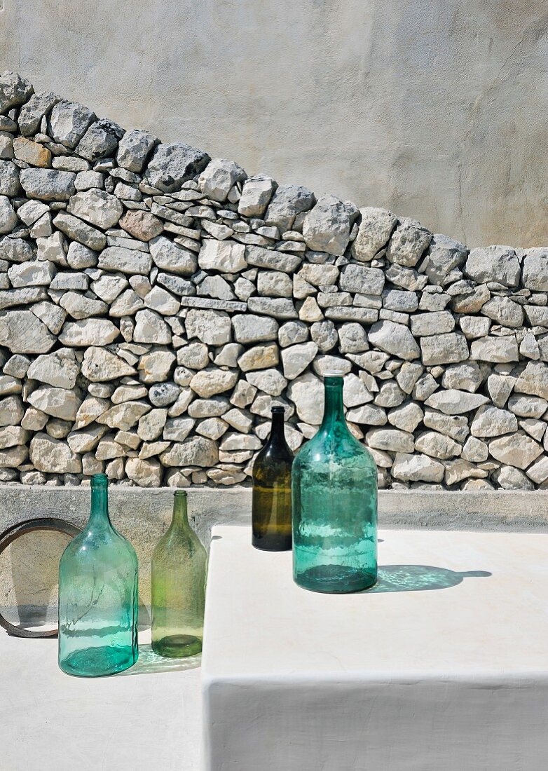 Arrangement of bottles in front of stone wall outside