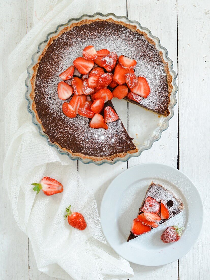 A chcolate tart topped with strawberries and icing sugar