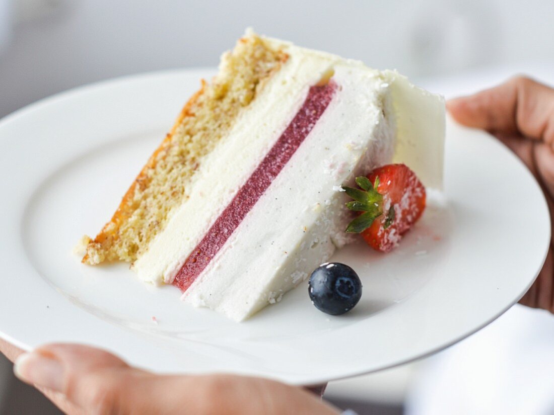 A slice of white chocolate mousse cake with strawberries and coconut