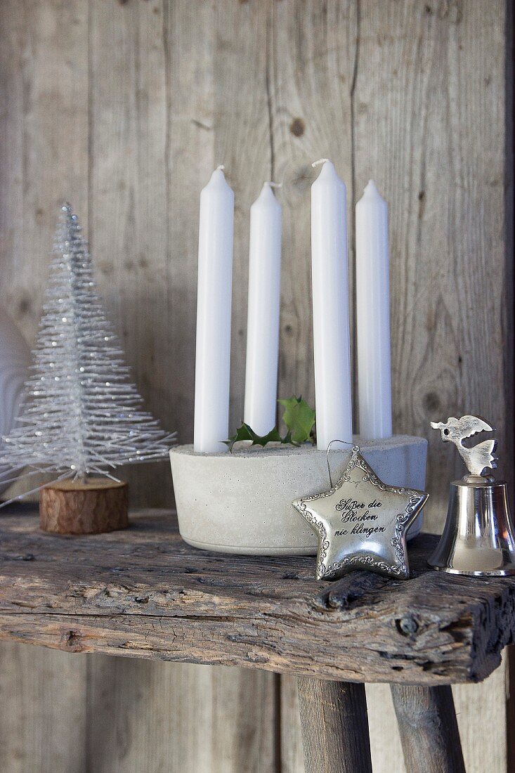 Candle arrangement, stylised Christmas tree, silver star and silver bell on wooden bench