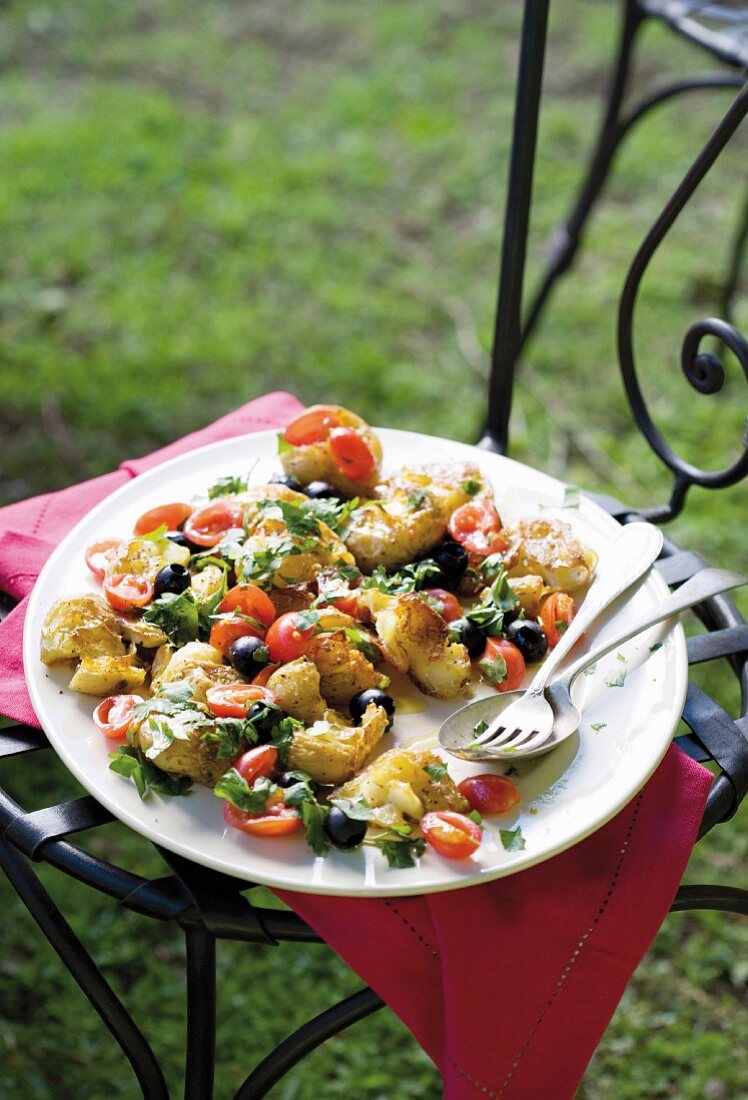 Smashed potatoes with black olives and tomatoes