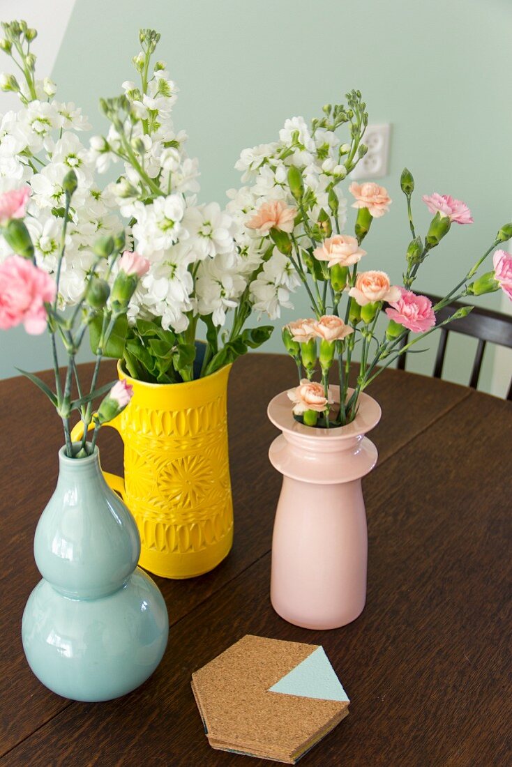 Flowers in vases of various colours and cork coasters