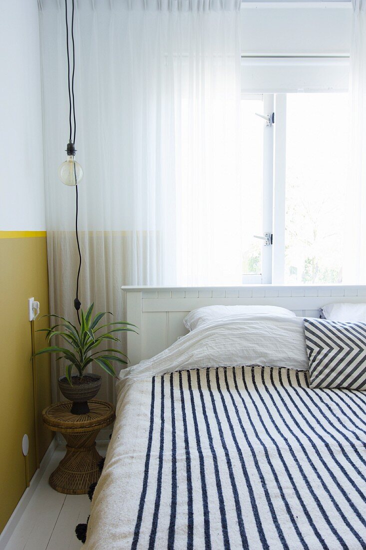 Black and white striped blanket on bed below window