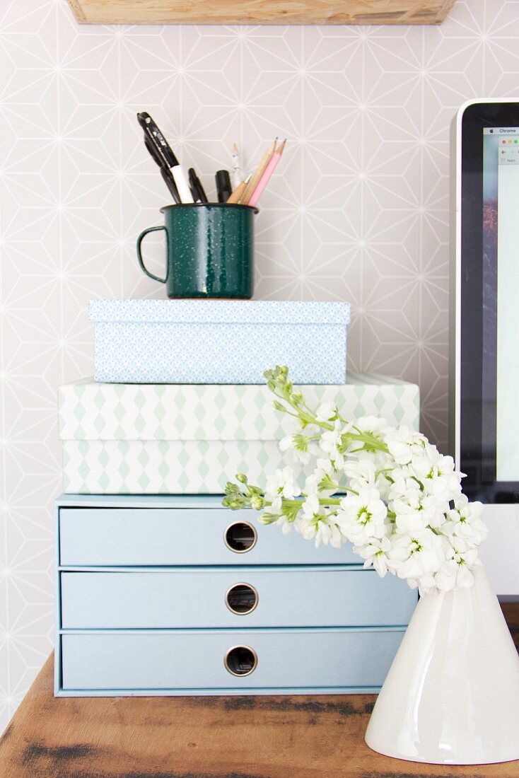 Flowers in front of small set of drawers and decorative boxes