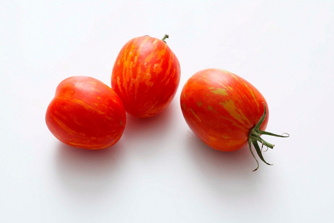 Drei gestreifte rote Tomaten vor weißem Hintergrund