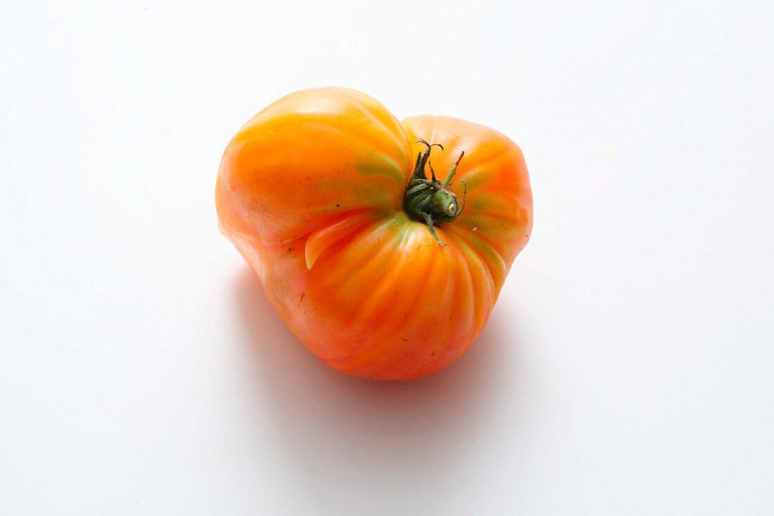 A yellow beefsteak tomato on a white surface