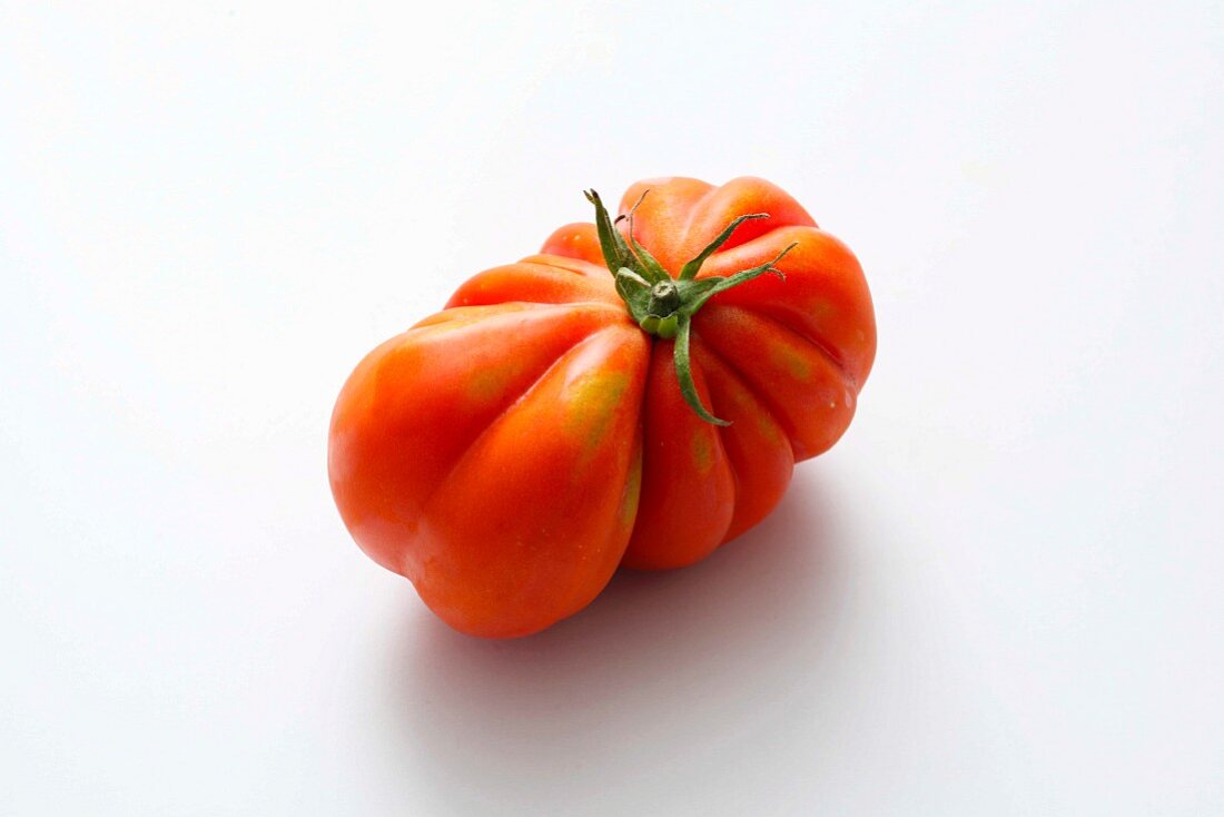 A red beefsteak tomato on a white surface