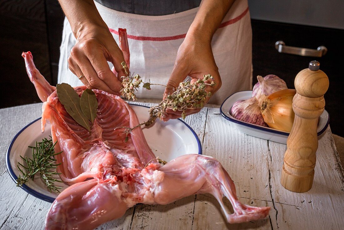 A woman preparing rabbit meat in a kitchen